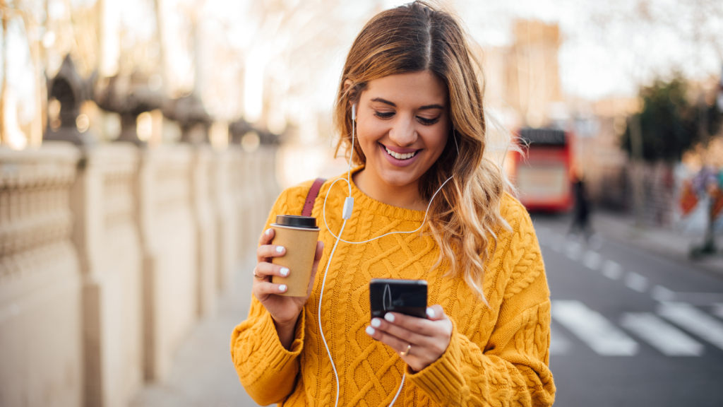 Girl on street with coffee checking her mobile